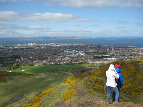 The view from atop Arthur's seat, showing Edinburgh's New Town stretching out to the sea. There's a guy wearing a beret in the frame.