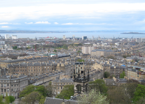 The rooftops of Edinburgh. In the background a long ridge of rock rises up to a lumpy peak.