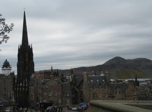 The rooftops of Edinburgh. In the background a long ridge of rock rises up to a lumpy peak.